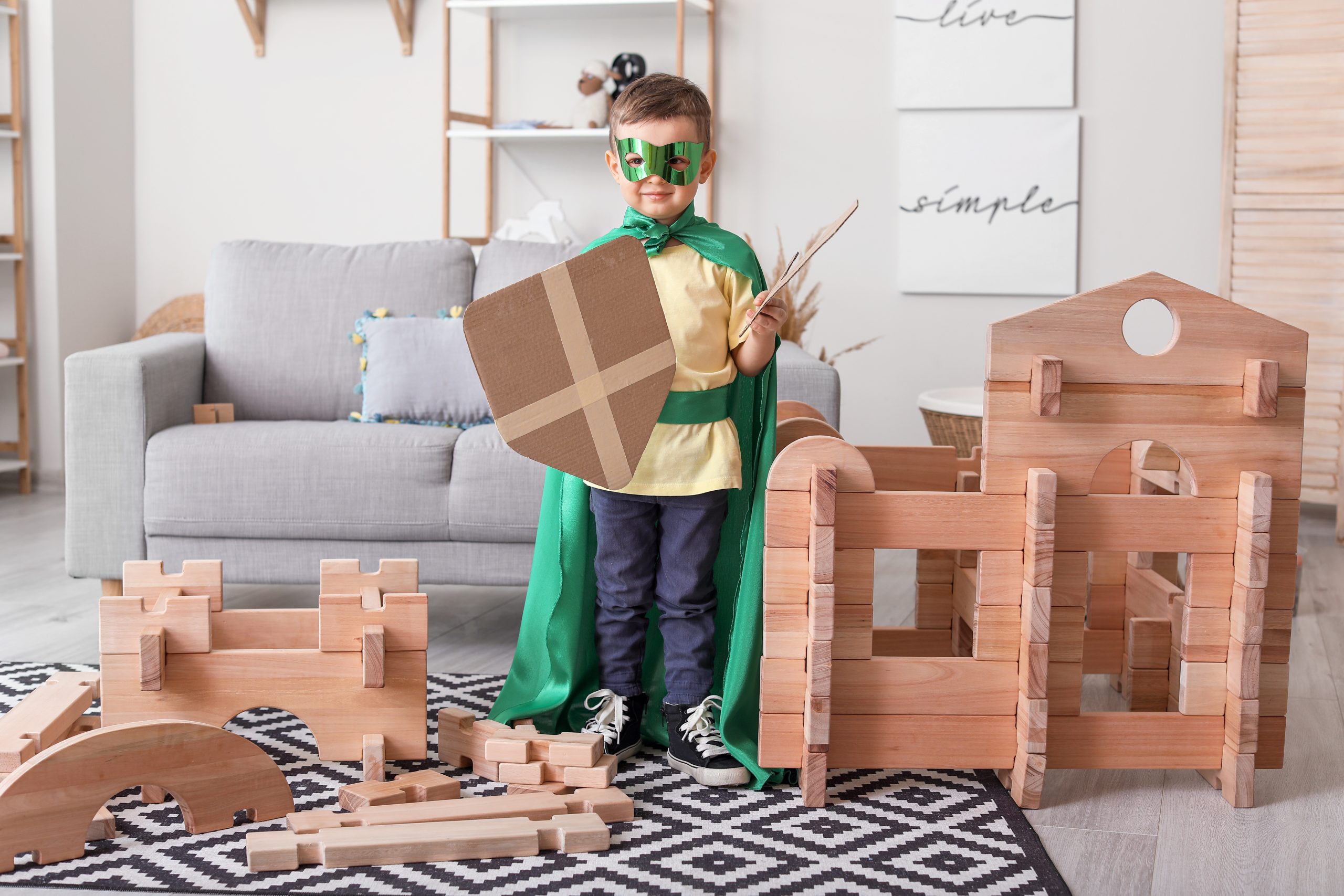 Little boy dressed as knight playing with take-apart house at home